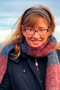 Politisk rådgjevar Martine Eliasson står på biletet ute i frisk luft. Ho har raudleg brunt hår med grått strikka panneband, blå jakke og eit tjukt, blått og rosa skjerf rundt halsen. Martine brukar briller, smiler til kamera og har brune auge.