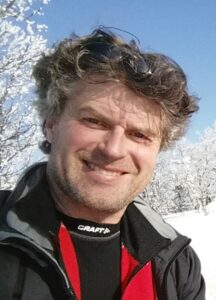 Morten Tangen er far og fungerende arbeidsleder for datteren sin. På bildet smiler han, han har lett bølgete gråstenket hår, svart jakke med røde detaljer, og han står ute i snøen. 