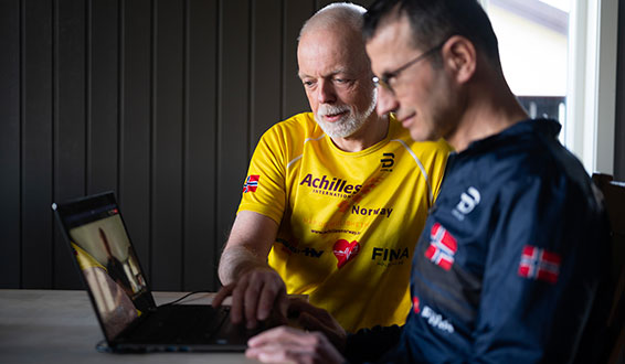 Mann jobber på PC med assistent ved siden av seg