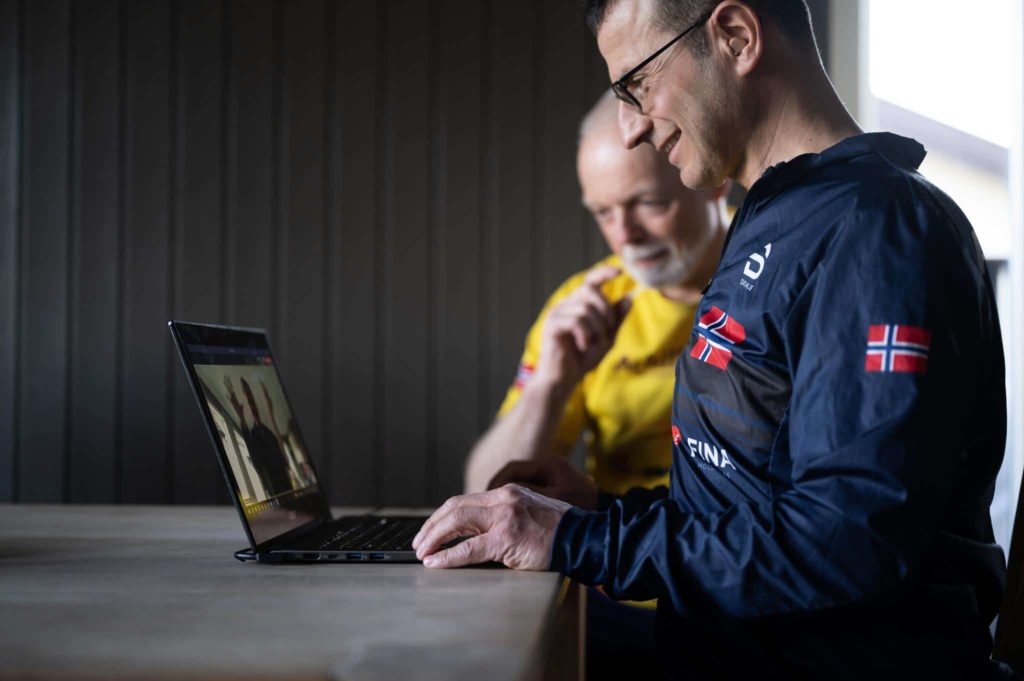 Mann ved laptop sammen med assistent