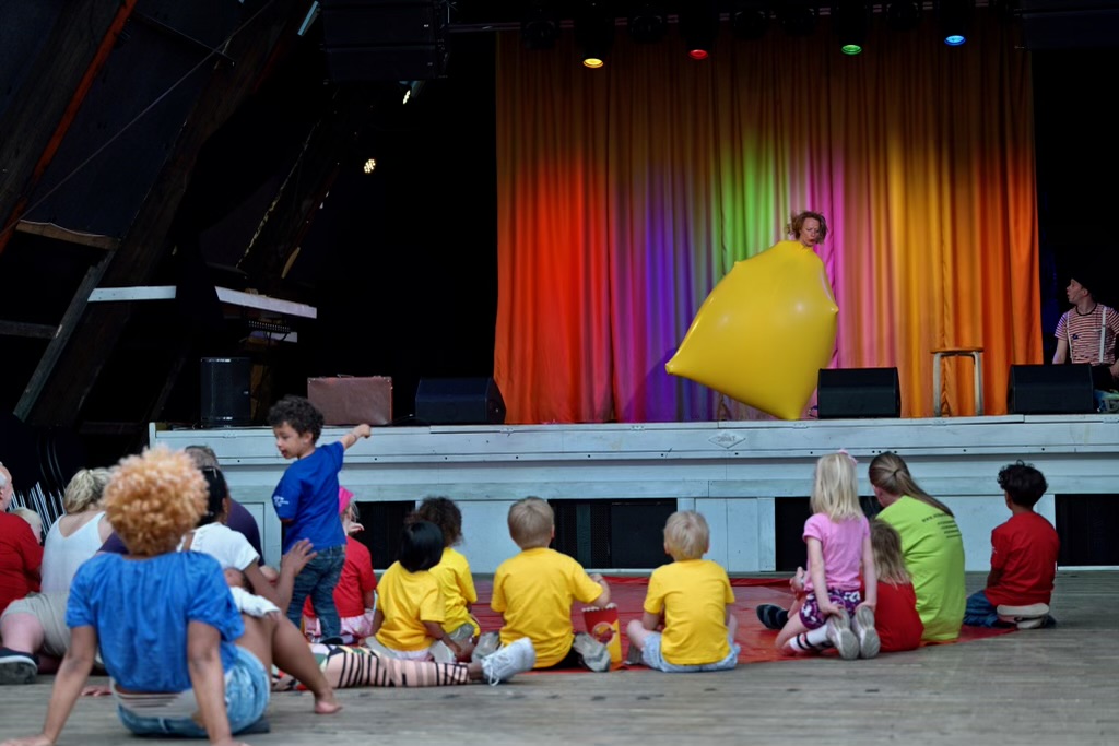 Show for de minste med duoen Plutselig Sirkus. En jente er inne i en stor gul ball, og beveger seg rundt på scenen. Barna sitter foran scenen, i festival-t-skjorter og beundrer det som skjer.