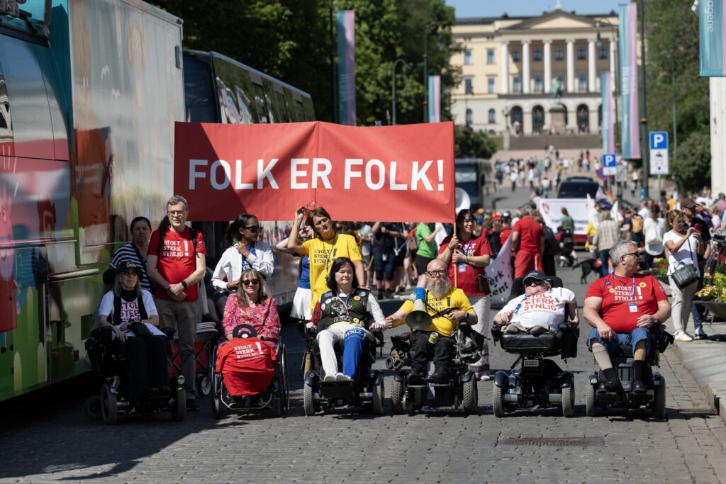 Ulobas grunnleggere og ledelse først i paraden, og bak de er parolene Folk er folk