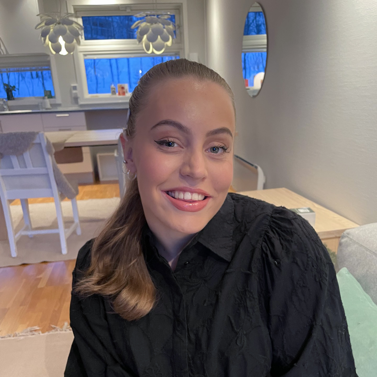 Bilde av Regine Elevoldt. Hun har langt mørkeblondt hår i hestehale, blå øyne, hun er pent sminket og smiler til kameraet. Hun har på seg en svart skjorte.