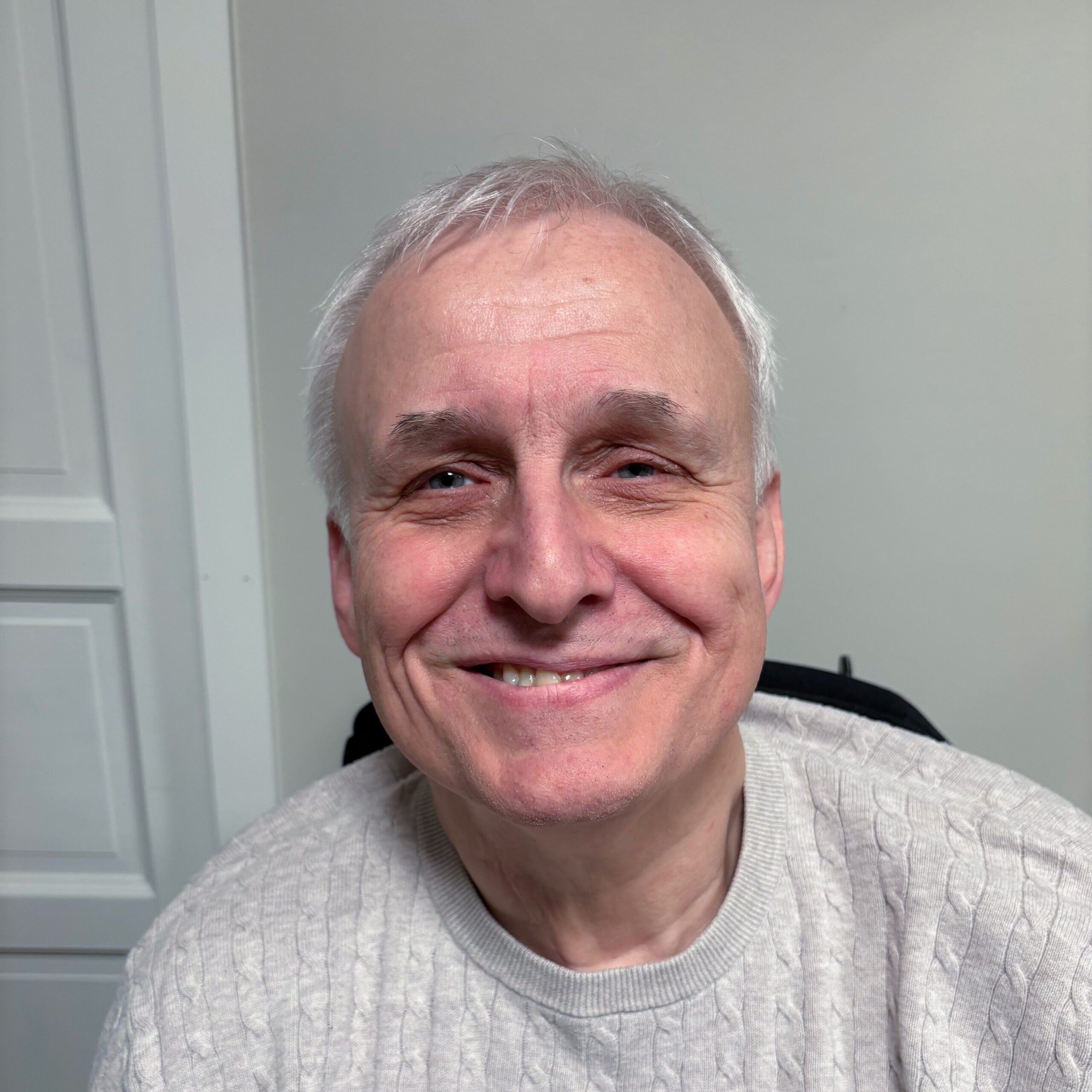 Svein Arne Vabø smiler til kameraet. Han har kort grått hår, litt mørkere øyebryn, blå øyne og et stort smil. Han har på seg en lysegrå strikkegenser.